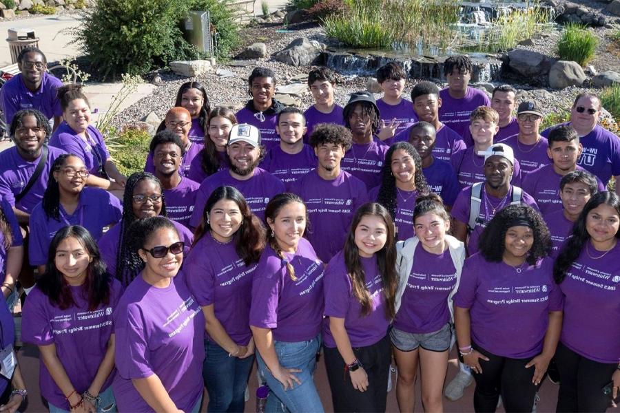 a large group of people wearing purple shirts pose for a photo outdoors.